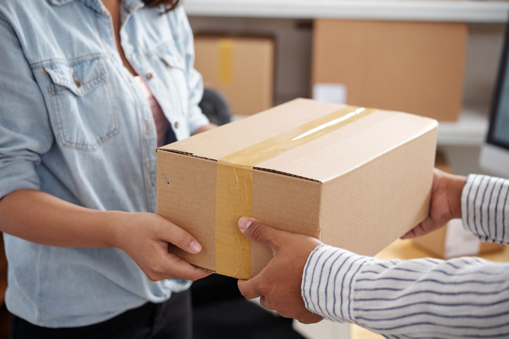 Close-up of woman receiving cardboard box from delivery man